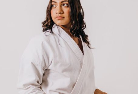 Student Discounts - A woman in a white karate uniform holding a red belt