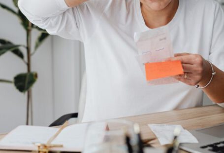 Costs - Woman at Desk Looking at Receipt and Scratching Her Head