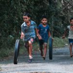 Kids Entertainment - Boys Running and Rolling Tires on Dirt Road in Forest