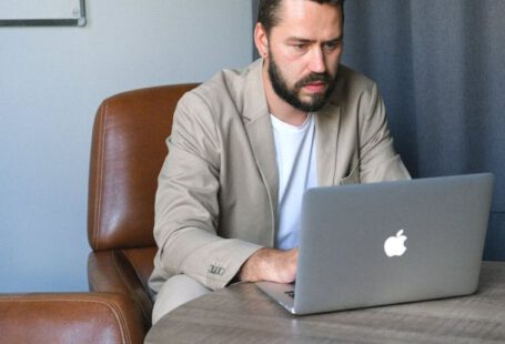 Reliable Internet - Concentrated bearded male entrepreneur wearing formal suit browsing netbook while working on startup
