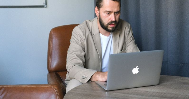 Reliable Internet - Concentrated bearded male entrepreneur wearing formal suit browsing netbook while working on startup